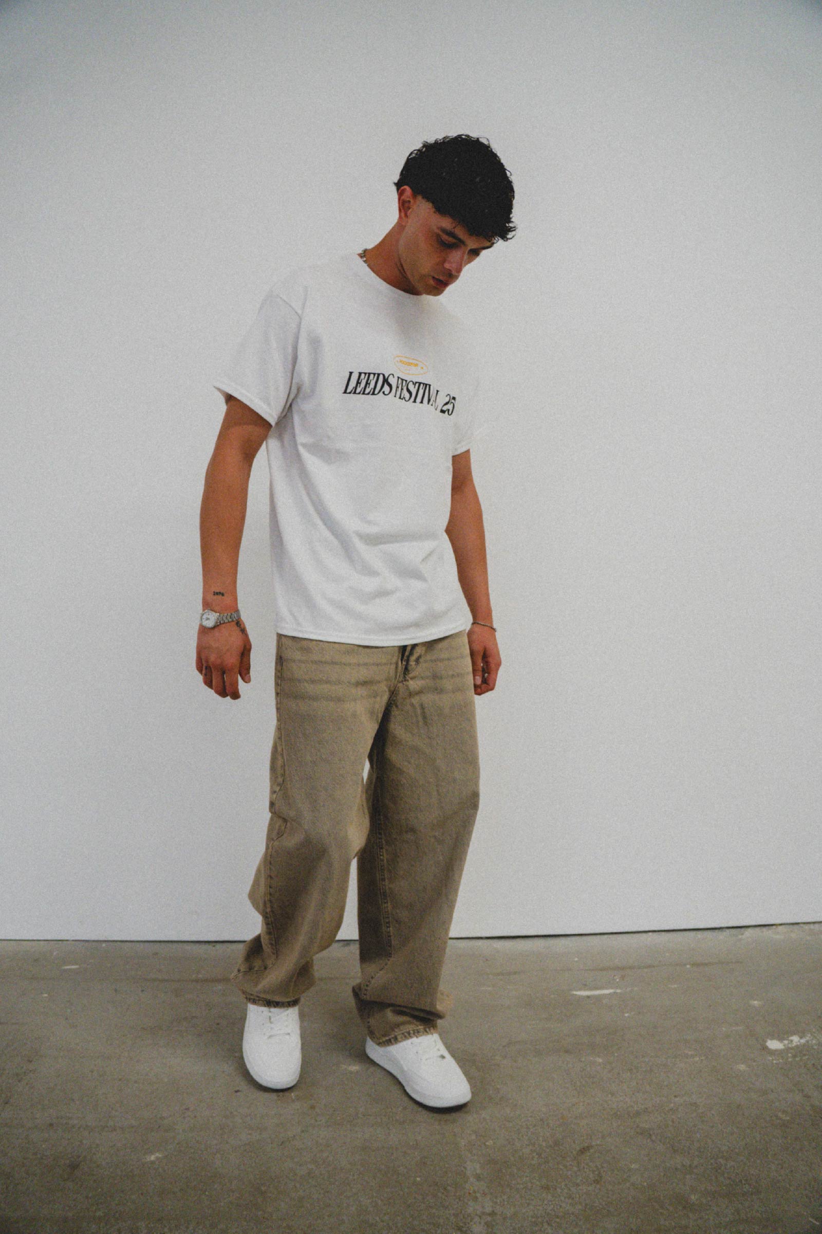 Three people pose in streetwear: one in a white t-shirt and black shorts, one in a black graphic t-shirt and blue jeans, and one in a black hoodie and black jeans, all wearing sunglasses.