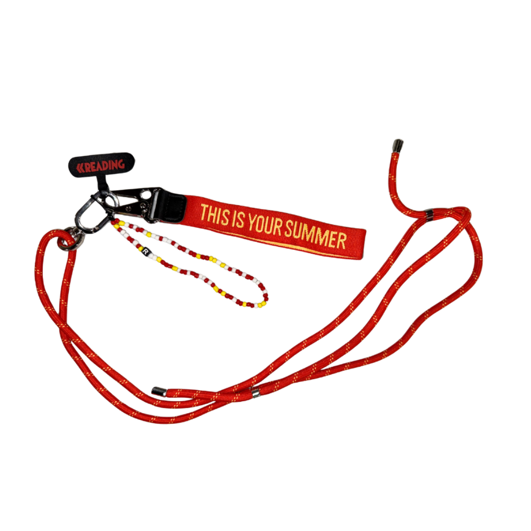 The 2025 Reading 2025 Phone Lanyard is a red lanyard with “THIS IS YOUR SUMMER” in yellow, a “READING” tag, white dotted ropes, a small beaded string, and an attached keychain.