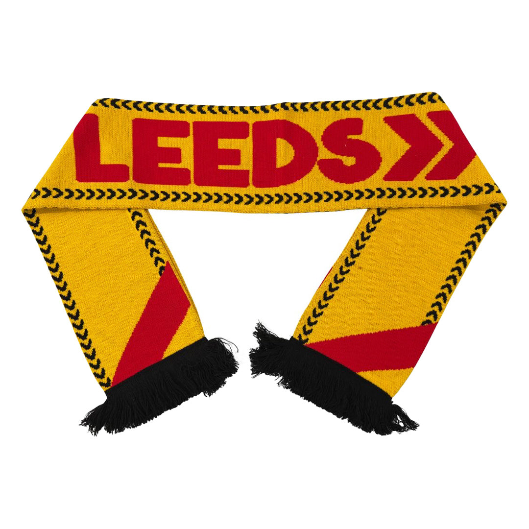 The Reading & Leeds Festival Leeds Scarf features yellow fabric with black and red patterns, bold red LEEDS lettering, and black fringes—an ideal accessory for festival fans.